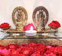 Golden colored idols of Indian deity Ganesh and Laxmi and placed in front of them a diya and flowers